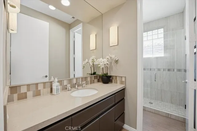 a bathroom with a granite countertop sink a mirror and a shower