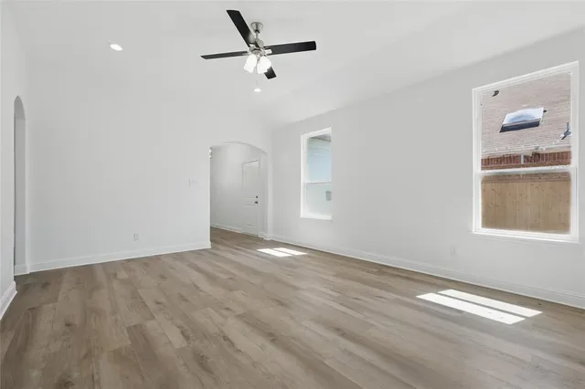 an empty room with wooden floor fan and windows