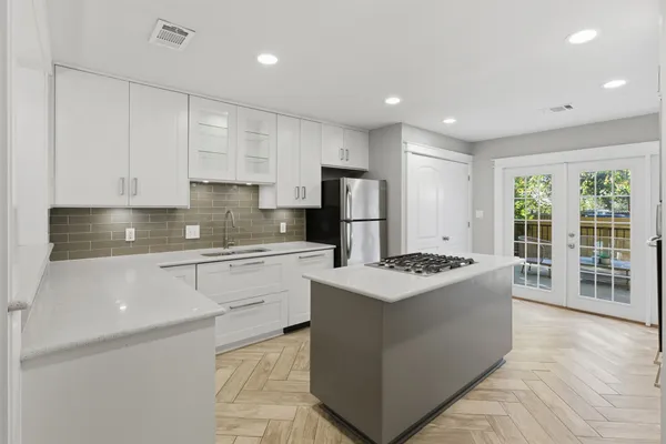 a kitchen with stainless steel appliances granite countertop a stove top oven a sink a refrigerator and white cabinets