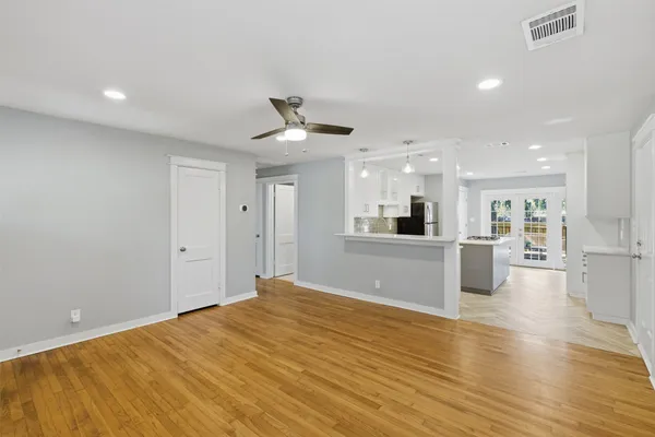 a view of a big room with wooden floor and a kitchen