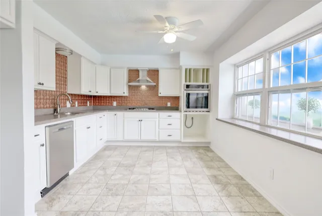 a large white kitchen with granite countertop a stove a sink dishwasher and a oven with white cabinets
