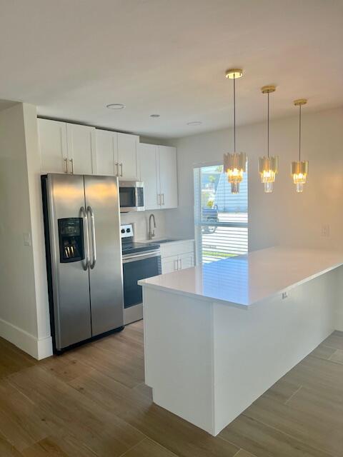 727 Hummingbird Way, Unit 1 North Palm Beach, FL 33408 - Photo 3 of 13 a kitchen with kitchen island a counter top space and stainless steel appliances