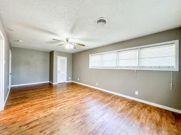 a view of an empty room with window and wooden floor