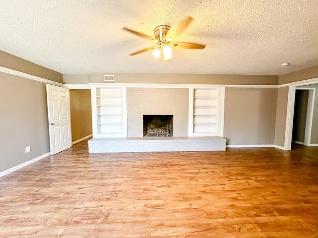 a view of an empty room with window and a kitchen