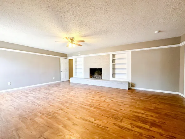 a view of an empty room with window and a kitchen