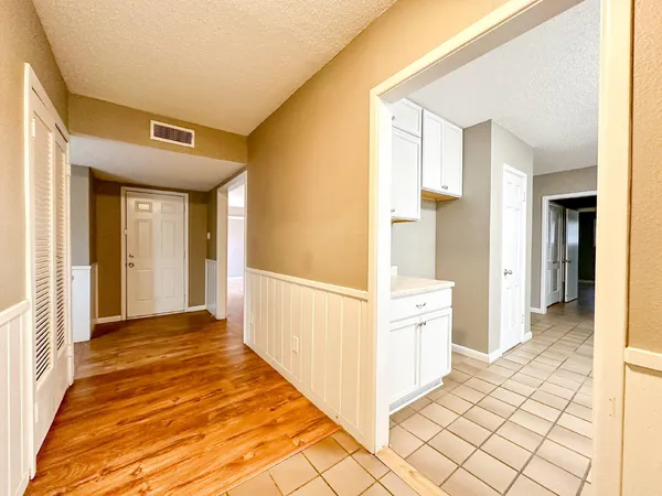 a view of a hallway with wooden floor and cabinet