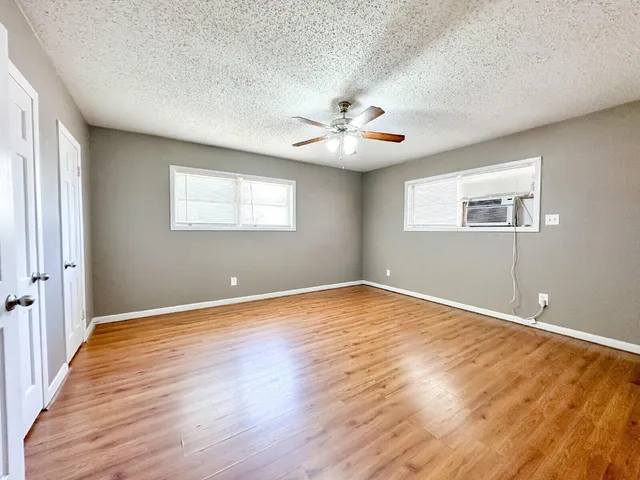 an empty room with wooden floor and windows