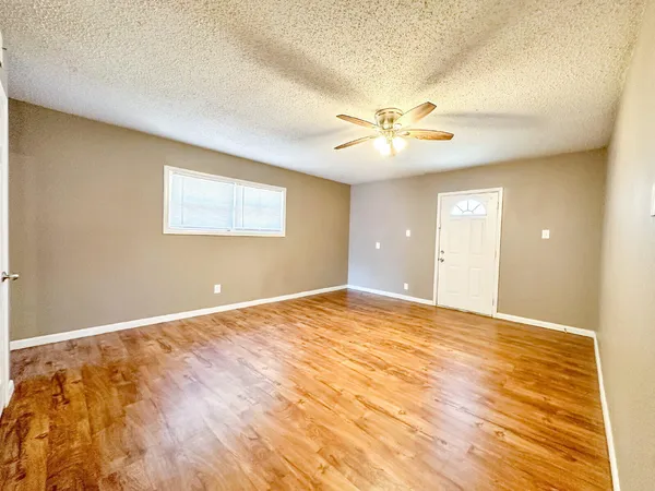 a view of an empty room with chandelier fan and a window