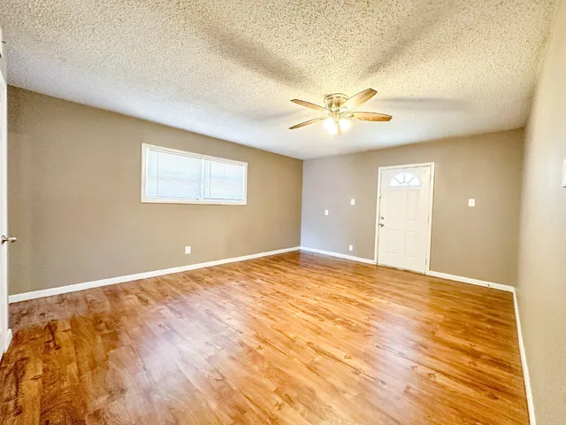 a view of an empty room with chandelier fan and a window