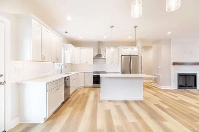 a kitchen with kitchen island a counter top space a refrigerator and cabinets