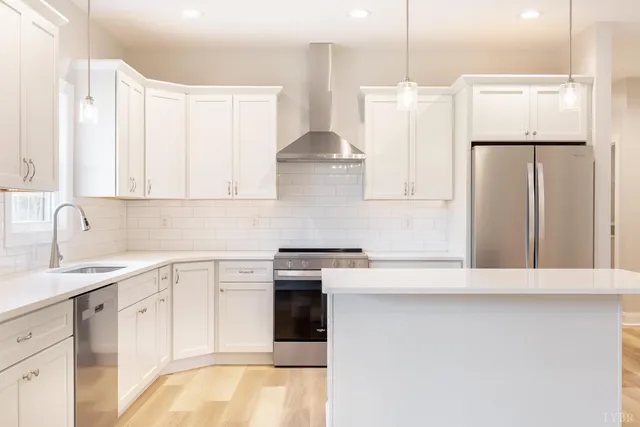 a kitchen with stainless steel appliances granite countertop a sink a stove and white cabinets