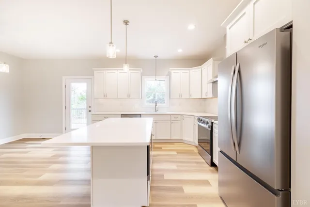 a kitchen with stainless steel appliances granite countertop a sink a stove and white cabinets with wooden floor