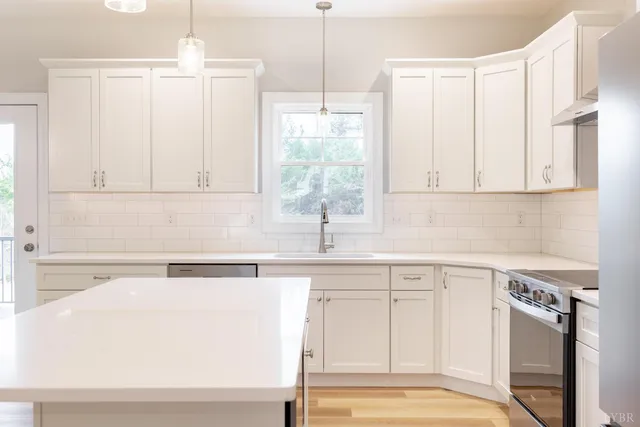 a view of kitchen with stainless steel appliances kitchen island refrigerator stove and white cabinets