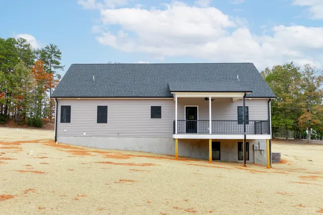 a front view of a house with yard and covered with trees