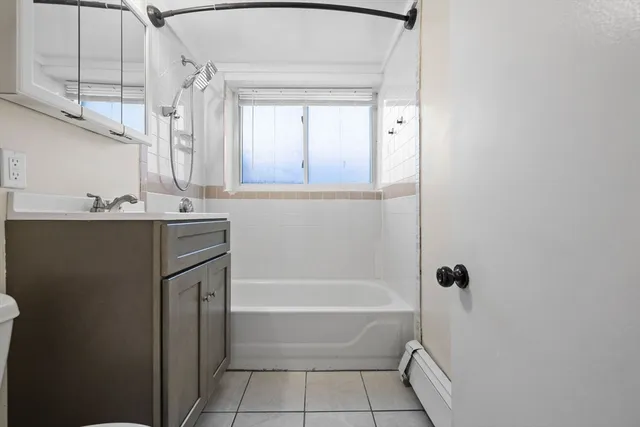 a bathroom with a bathtub a mirror a vanity and a shower