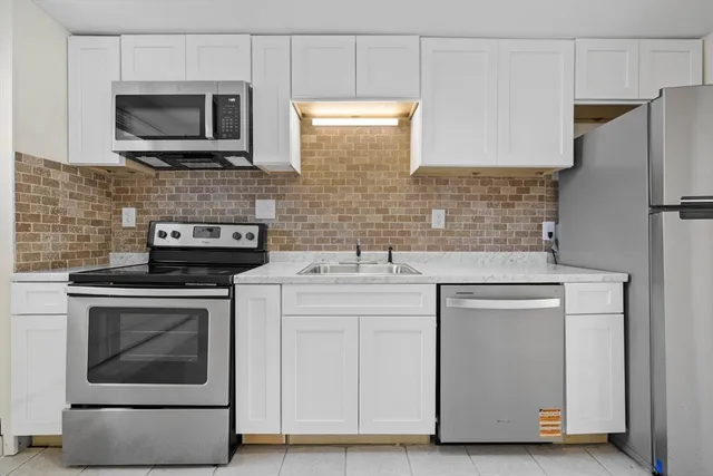 a kitchen with white cabinets stainless steel appliances and sink