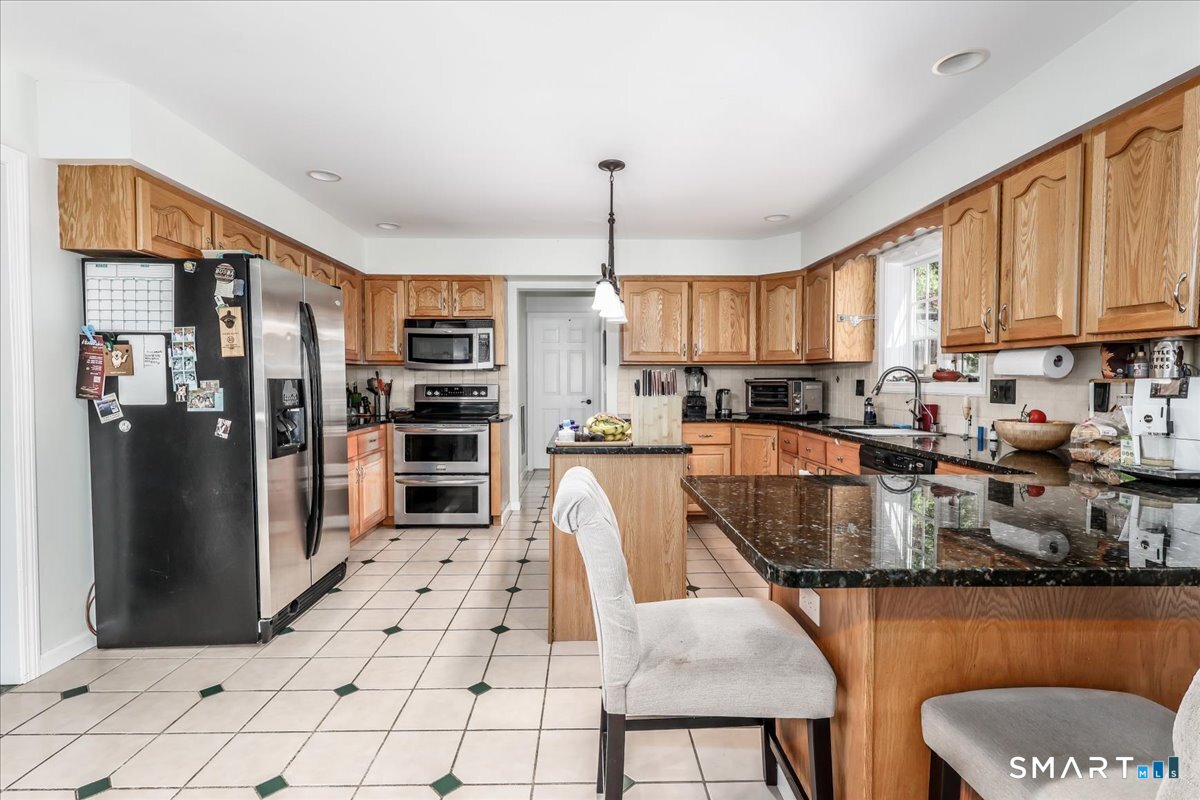 55 A Flax Hill Road Brookfield, CT 06804 - Photo 11 of 40 a kitchen with stainless steel appliances granite countertop a refrigerator a stove and a sink with wooden floor
