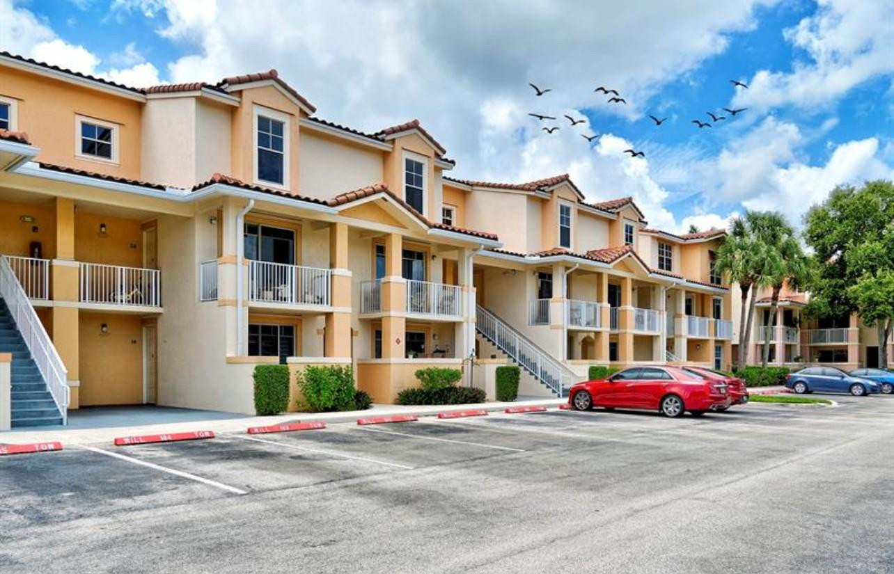 4784 Central Boulevard, Unit 22 Jupiter, FL 33458 - Photo 16 of 18 a front view of a building with lot of cars and trees