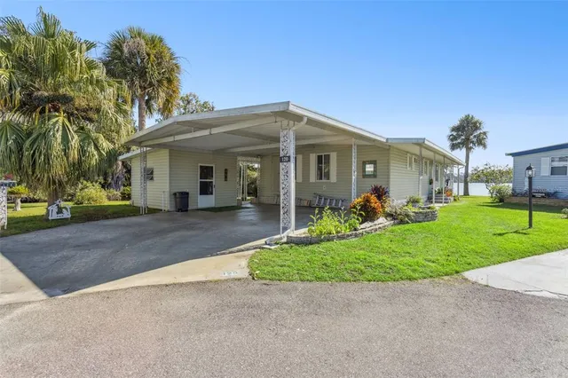 a view of a white house with a big yard and potted plants