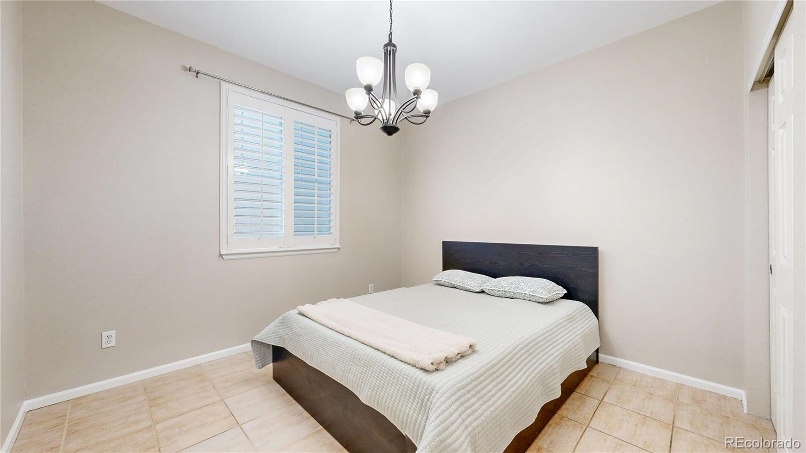 10797 Hickory Ridge Street Highlands Ranch, CO 80126 - Photo 12 of 42 a bedroom with a bed and a chandelier