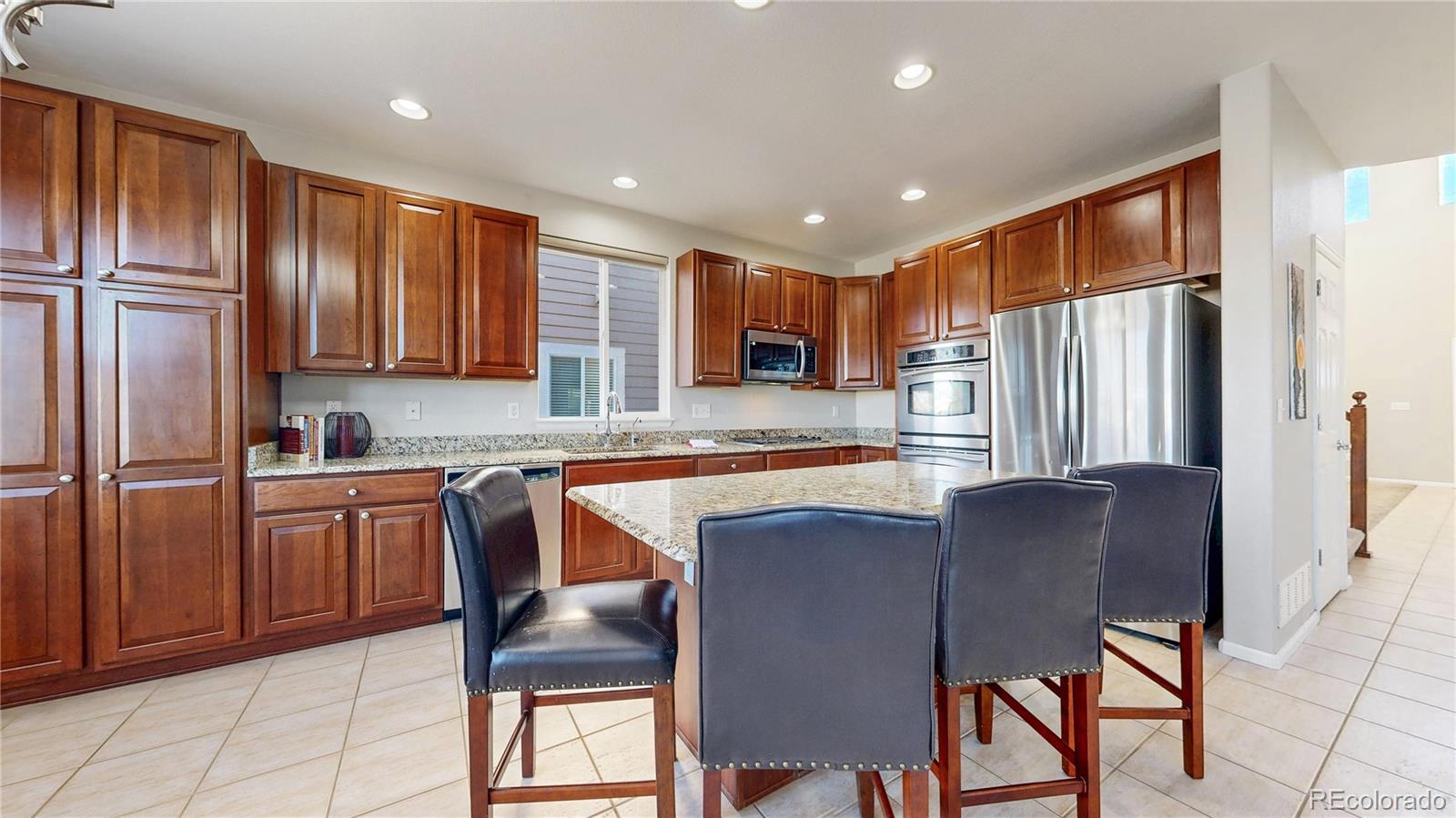 10797 Hickory Ridge Street Highlands Ranch, CO 80126 - Photo 2 of 42 a kitchen with stainless steel appliances granite countertop wooden cabinets a refrigerator stove top oven and sink