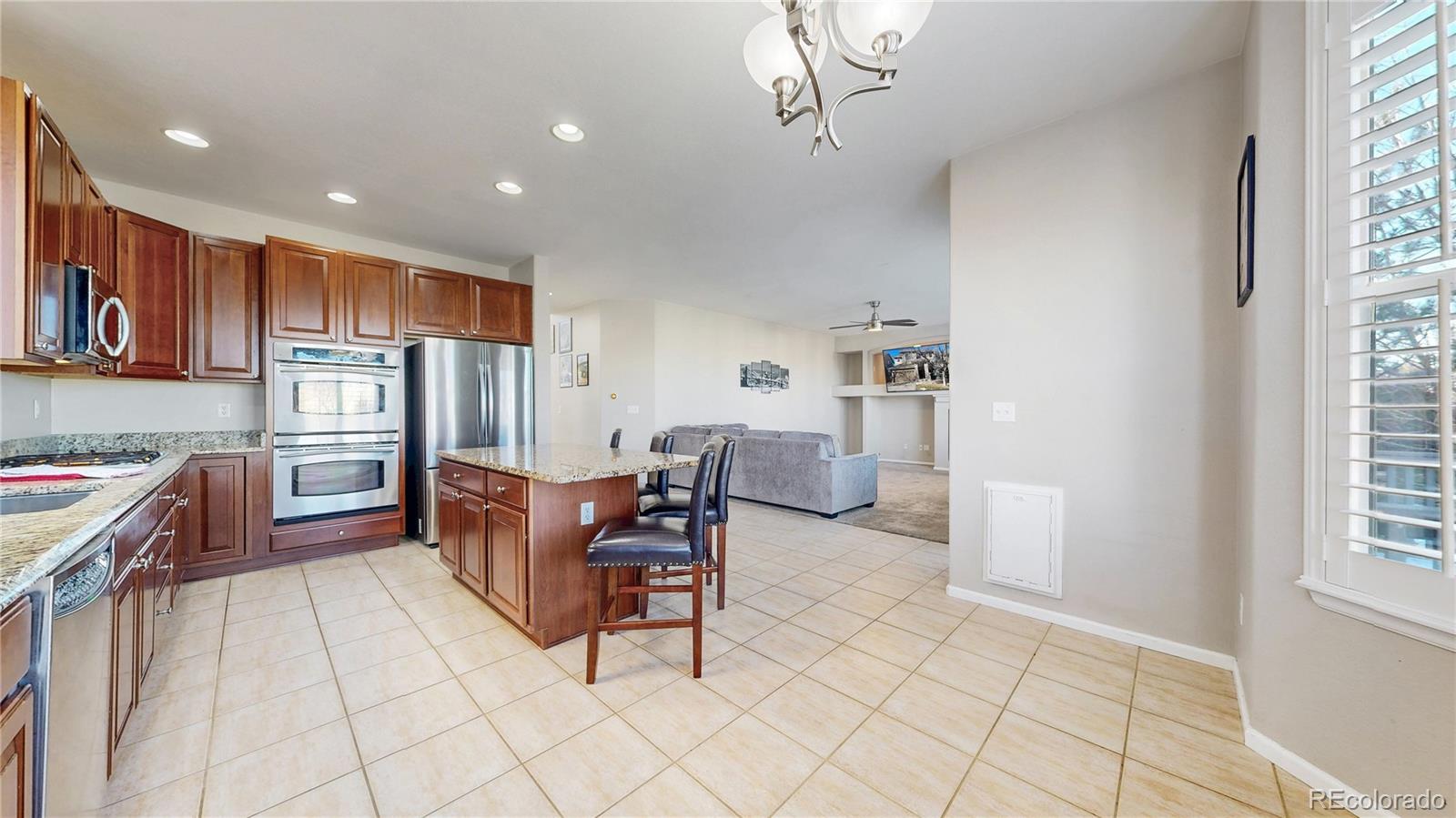 10797 Hickory Ridge Street Highlands Ranch, CO 80126 - Photo 3 of 42 a kitchen with stainless steel appliances kitchen island granite countertop a refrigerator and a stove top oven