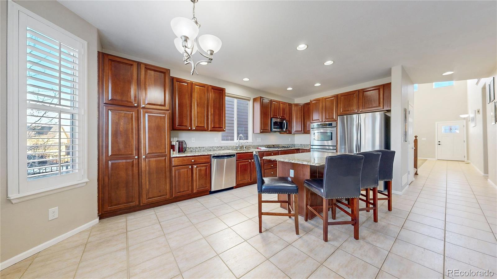 10797 Hickory Ridge Street Highlands Ranch, CO 80126 - Photo 9 of 42 a kitchen with stainless steel appliances granite countertop a refrigerator a stove top oven and a sink with granite countertops