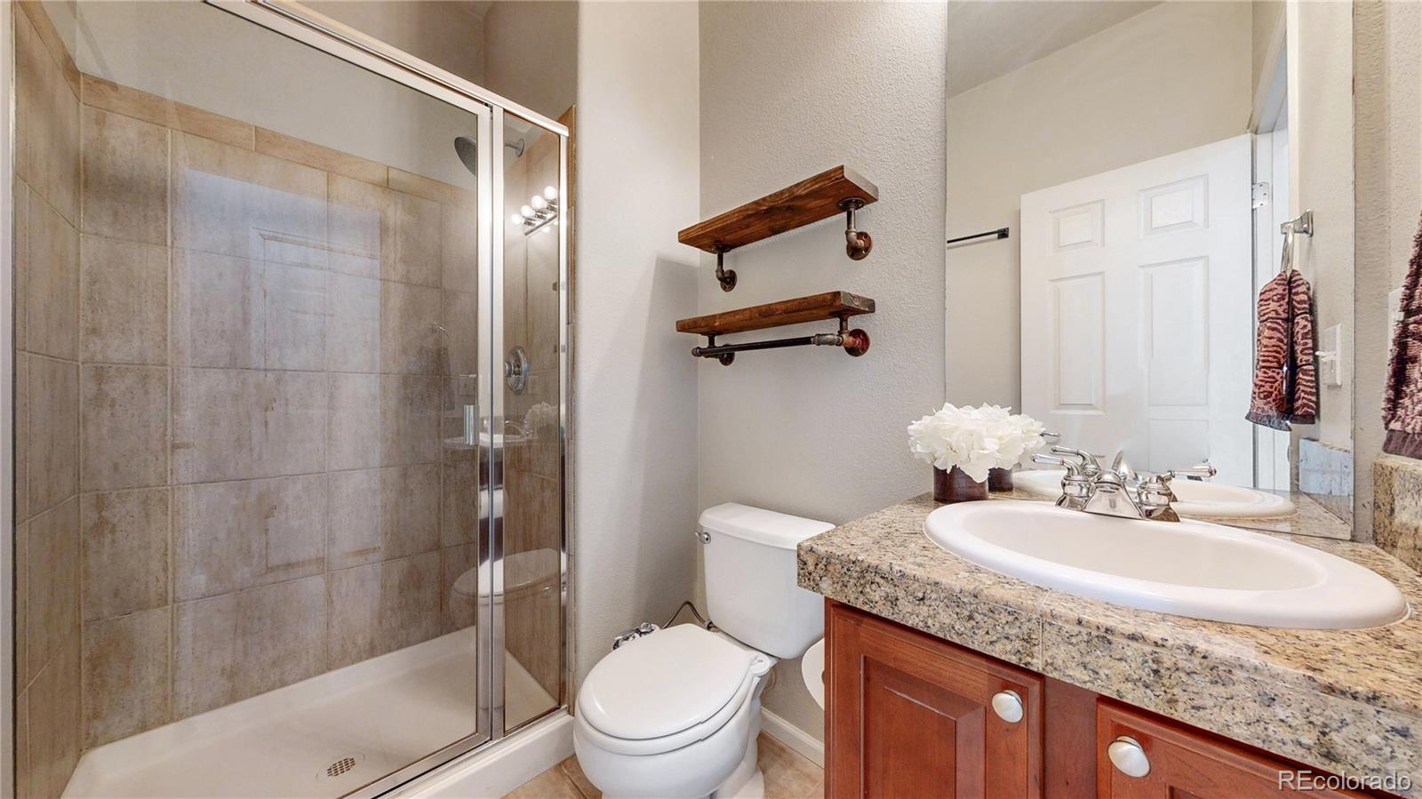 10797 Hickory Ridge Street Highlands Ranch, CO 80126 - Photo 10 of 42 a bathroom with a granite countertop sink toilet and shower