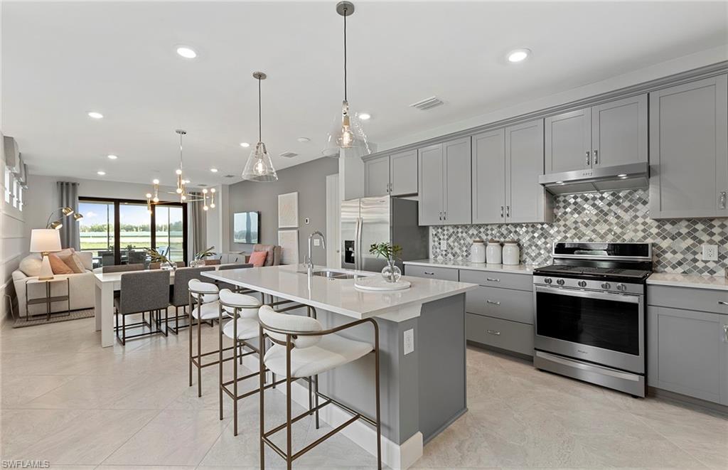 2142 Yellowfin Circle Naples, FL 34114 - Photo 9 of 31 a kitchen with stainless steel appliances kitchen island granite countertop a stove a sink a dining table and chairs