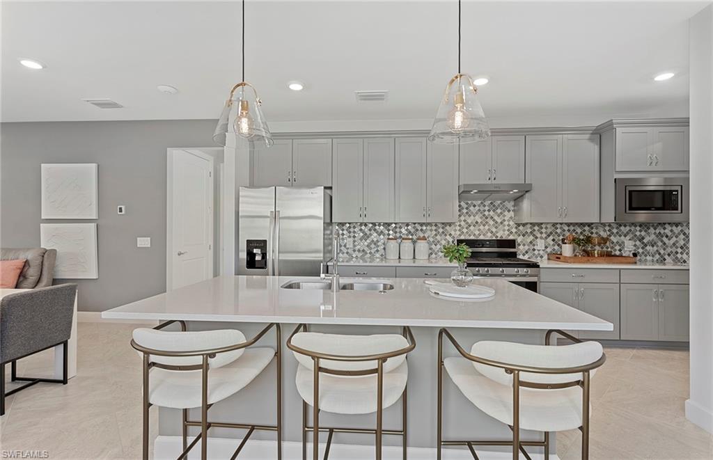 2142 Yellowfin Circle Naples, FL 34114 - Photo 10 of 31 a kitchen with kitchen island granite countertop a sink and a refrigerator
