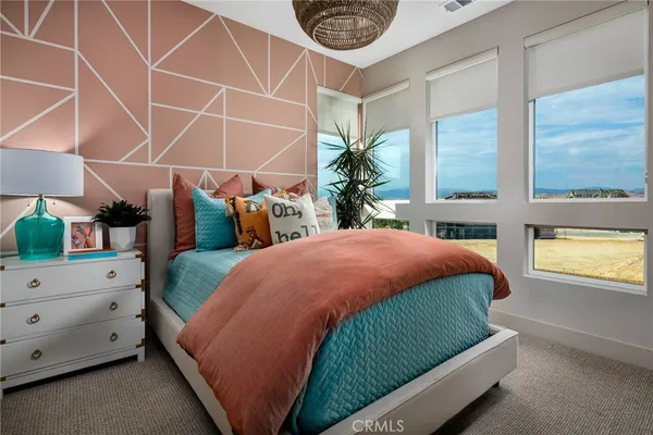 a bedroom with bed and a lamp on dresser