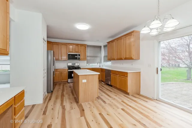 a kitchen with granite countertop a stove a sink dishwasher and a refrigerator with wooden floor