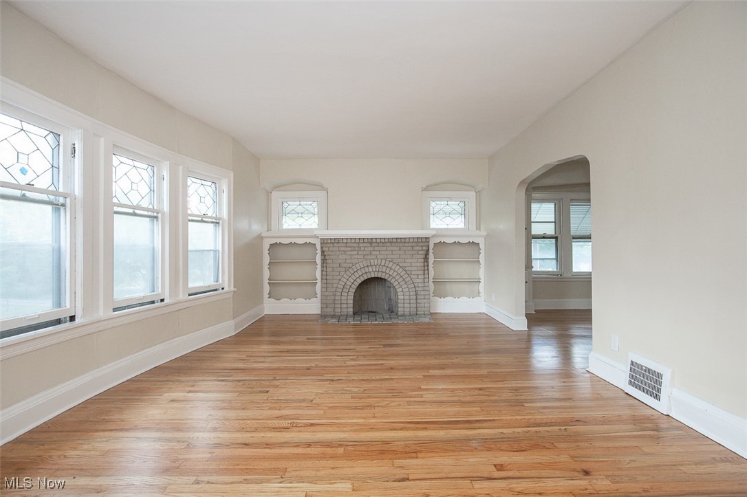 3616 Hildana Road Cleveland, OH 44120 - Photo 10 of 27 Unfurnished living room featuring light wood-style floors, arched walkways, and a brick fireplace