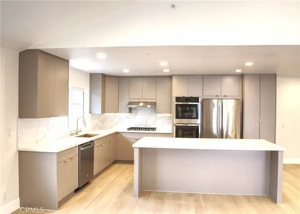 a large kitchen with a large counter top stainless steel appliances and cabinets