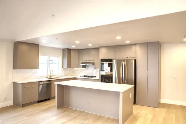 a kitchen with stainless steel appliances a sink a stove a refrigerator and cabinets