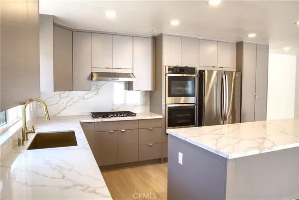 a kitchen with stainless steel appliances kitchen island granite countertop a refrigerator a stove and a sink