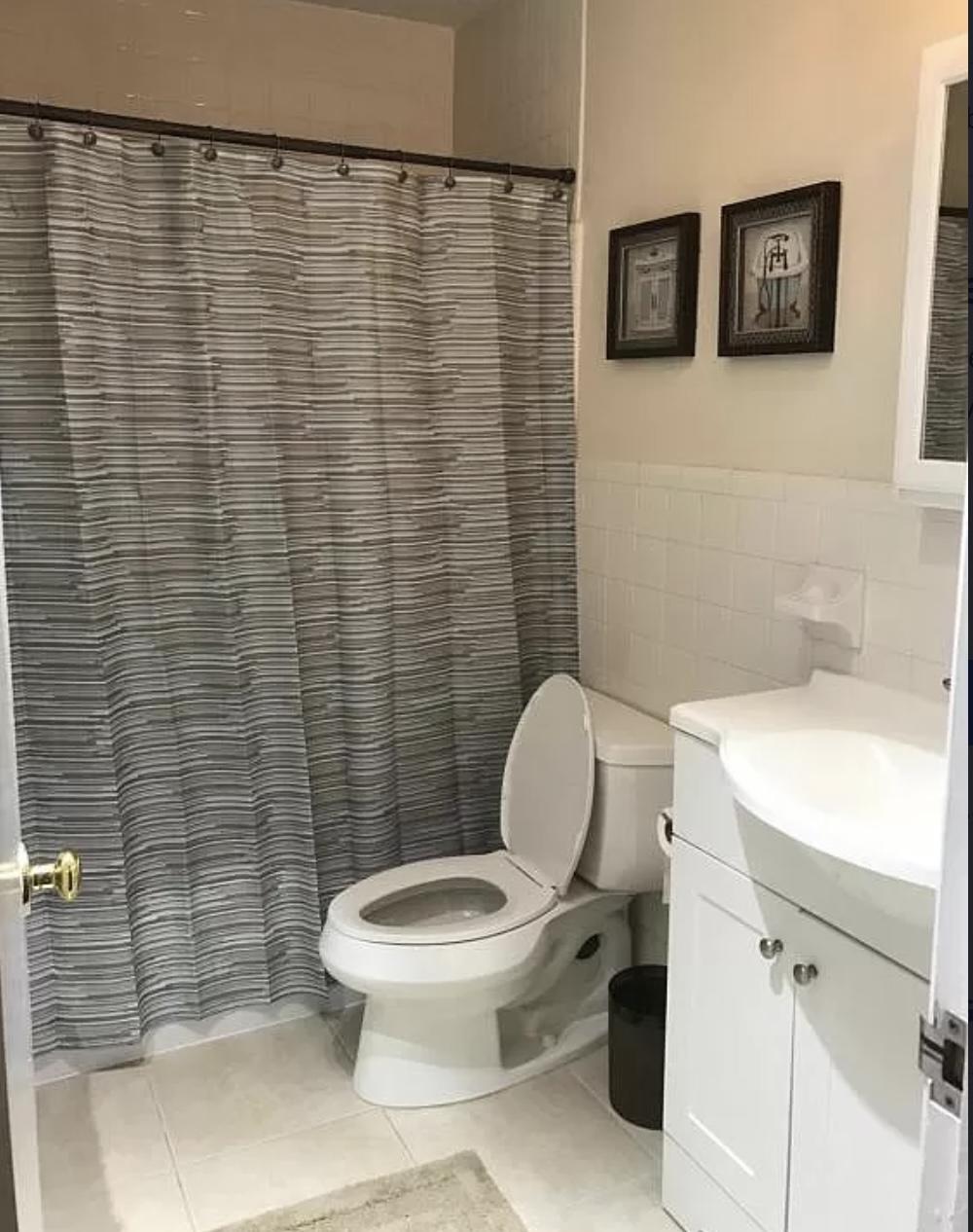 27 Pinehurst Lane Boca Raton, FL 33431 - Photo 9 of 12 a white toilet sitting next to a white sink and a shower curtain