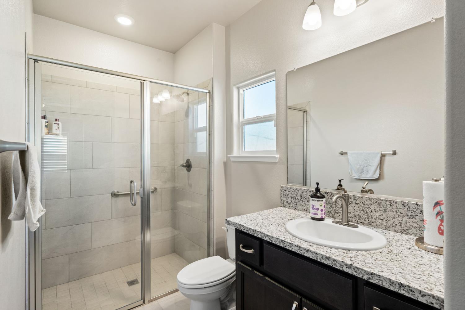 948 Hogan Road Galt, CA 95632 - Photo 15 of 20 a bathroom with a granite countertop sink toilet and shower