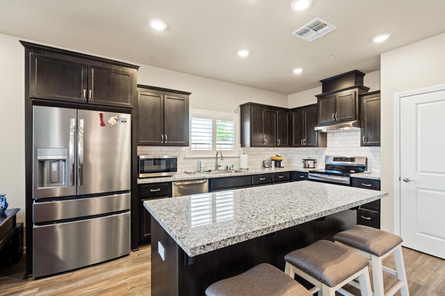 948 Hogan Road Galt, CA 95632 - Photo 7 of 20 a kitchen with granite countertop a refrigerator and wooden cabinets