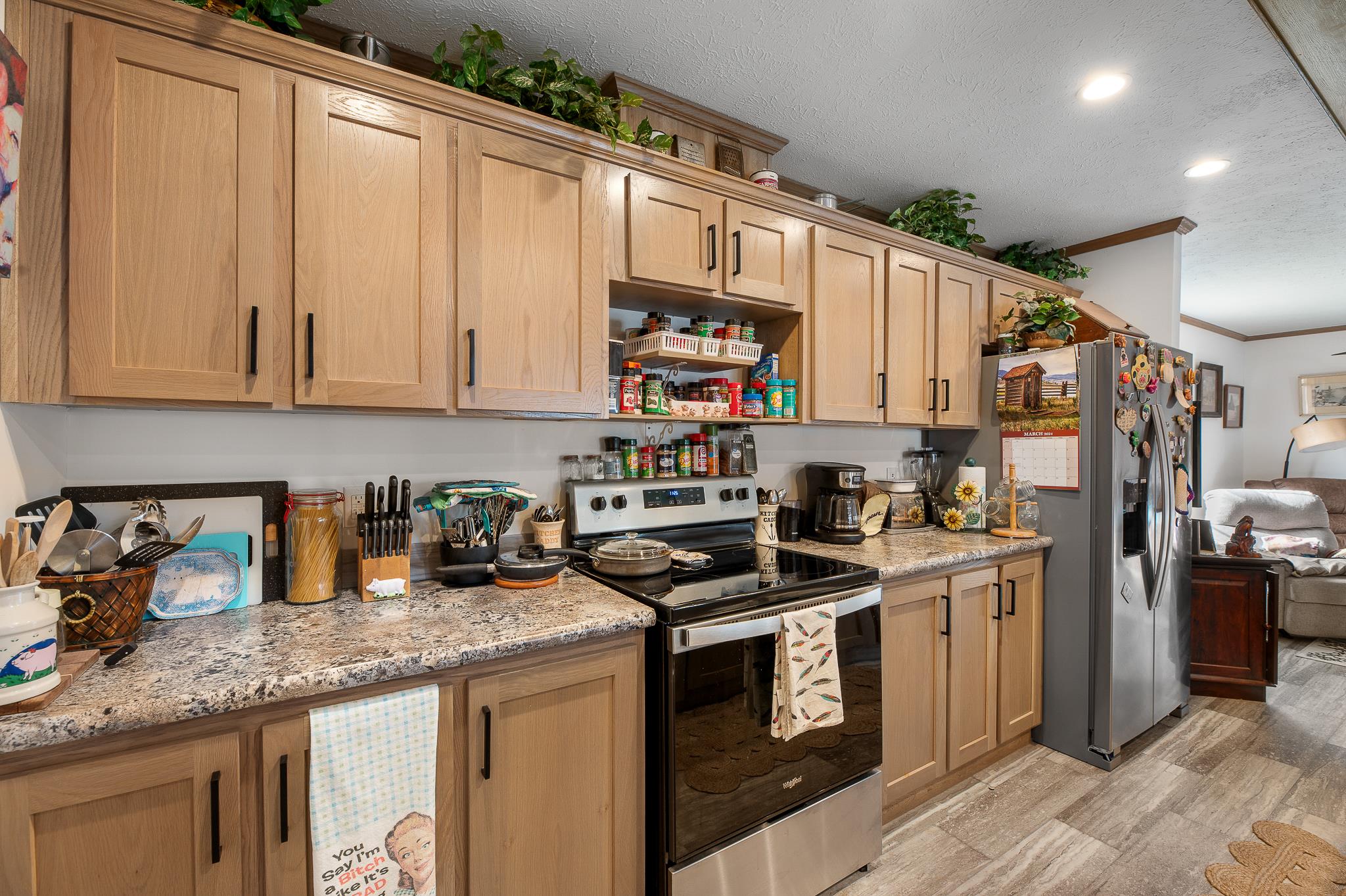 1040 Round Butte Road, Unit 34 Ronan, MT 59864 - Photo 12 of 30 Kitchen featuring light brown cabinetry, appliances with stainless steel finishes, a textured ceiling, and light stone counters