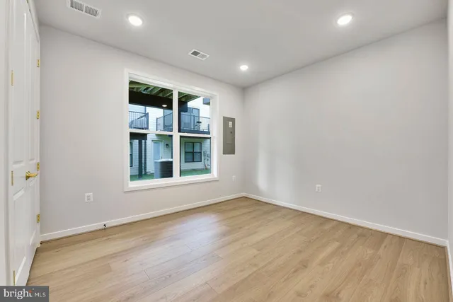 an empty room with wooden floor and windows