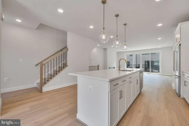 a large white kitchen with lots of counter space cabinets and wooden floor