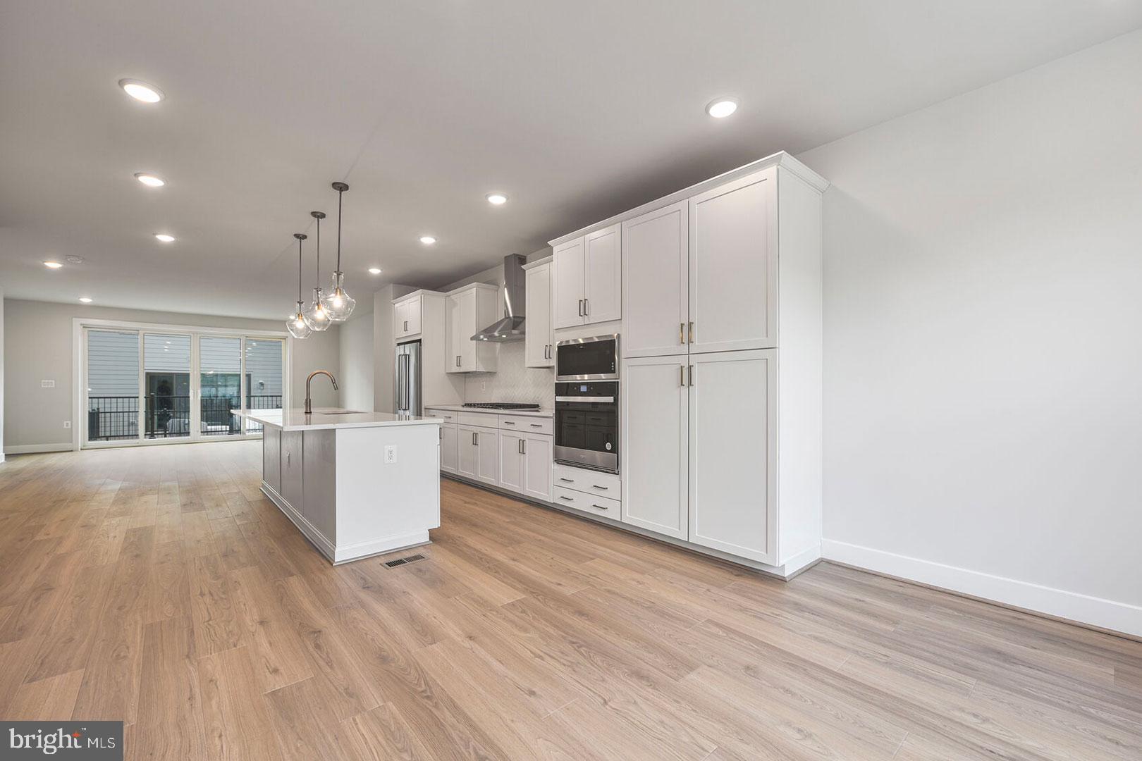 1624 Fellowship Square Reston, VA 20190 - Photo 6 of 18 a large white kitchen with kitchen island a stove a refrigerator cabinets and wooden floor