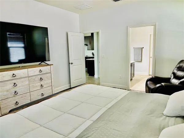 a bedroom with a bed and a flat tv screen on dresser