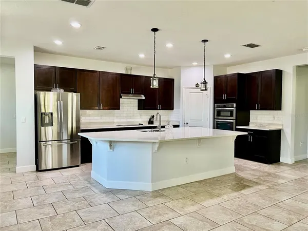 a kitchen with stainless steel appliances granite countertop a refrigerator a sink a stove a microwave and a refrigerator