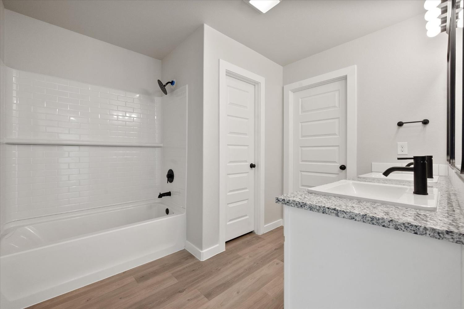 7429 30th Street Lubbock, TX 79407 - Photo 14 of 20 a bathroom with a granite countertop sink a toilet and bathtub