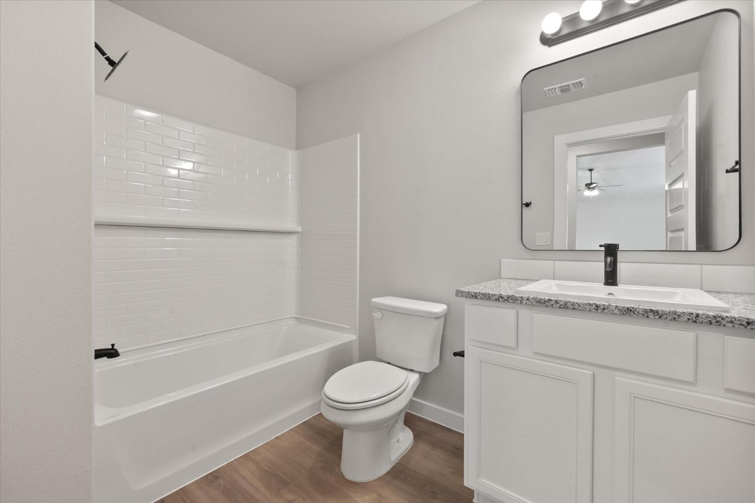 7429 30th Street Lubbock, TX 79407 - Photo 18 of 20 a bathroom with a granite countertop toilet a sink and a mirror