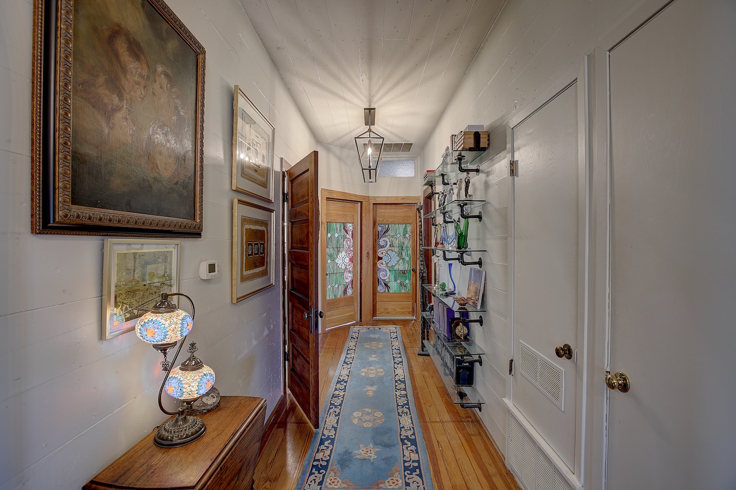 1903 South Austin Avenue Georgetown, TX 78626 - Photo 25 of 40 Even this pretty hallway works hard. the 2 doors at the end go to the hall bath (right) and the Breakfast room (Left) Custom made doors show off the stained glass inserts that glow like magic when the light shines through.