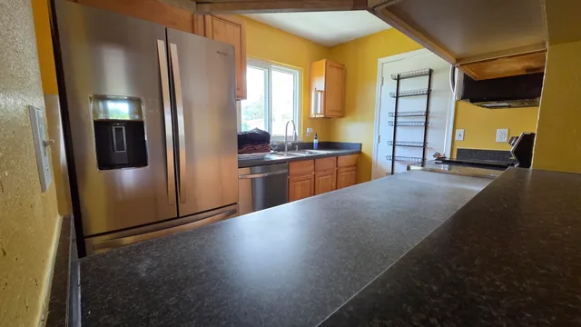 a kitchen with stainless steel appliances granite countertop a refrigerator a stove and a sink with wooden floor