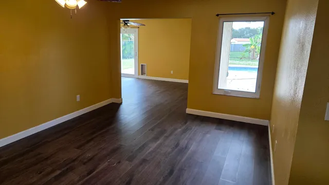 a view of an empty room with wooden floor and a window